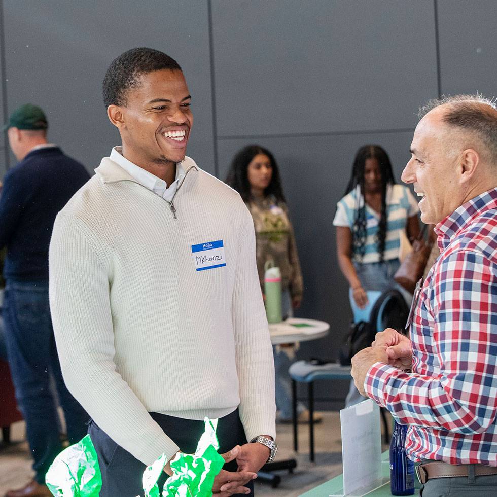 A student smiles while standing in front of a parent at Career Jam held in the Billie Tisch Center for Integrated Sciences