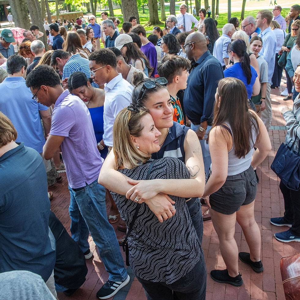 A student hugs a family member in a crowd of seniors while celebrating the brick ceremony in Case Green