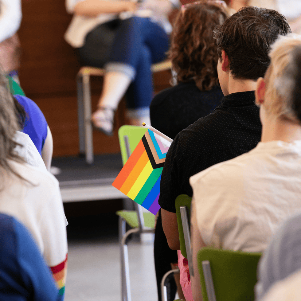 Student holds an inclusion flag during panel discussion in Skidmore's Wycoff Center