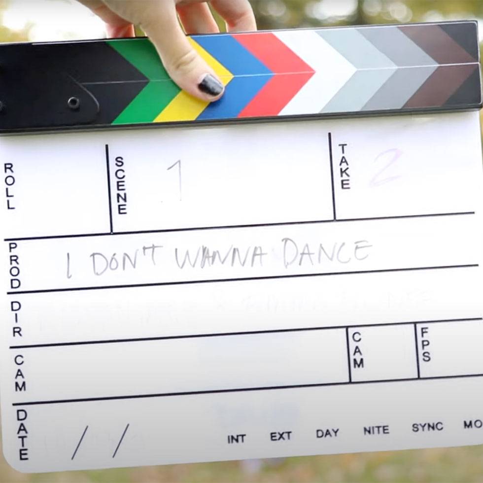 A hand holds a filming clapperboard with production title "I don't wanna dance" on it