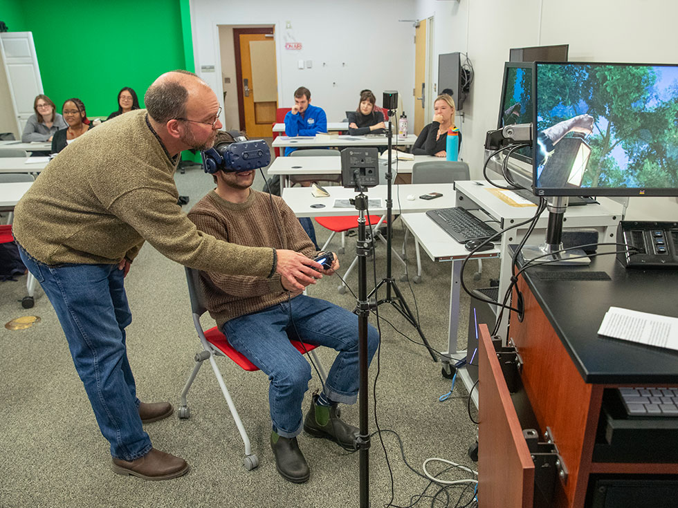 Skidmore College professor Jamie Parra talks to students in the Walden's Depths english class exploring virtual reality of Henry David Thoreau's Walden Pond in the LEDS lab with Ben Harwood, a Learning Experience Designer with the Learning Experience Design & Digital Scholarship Support (LEDS)