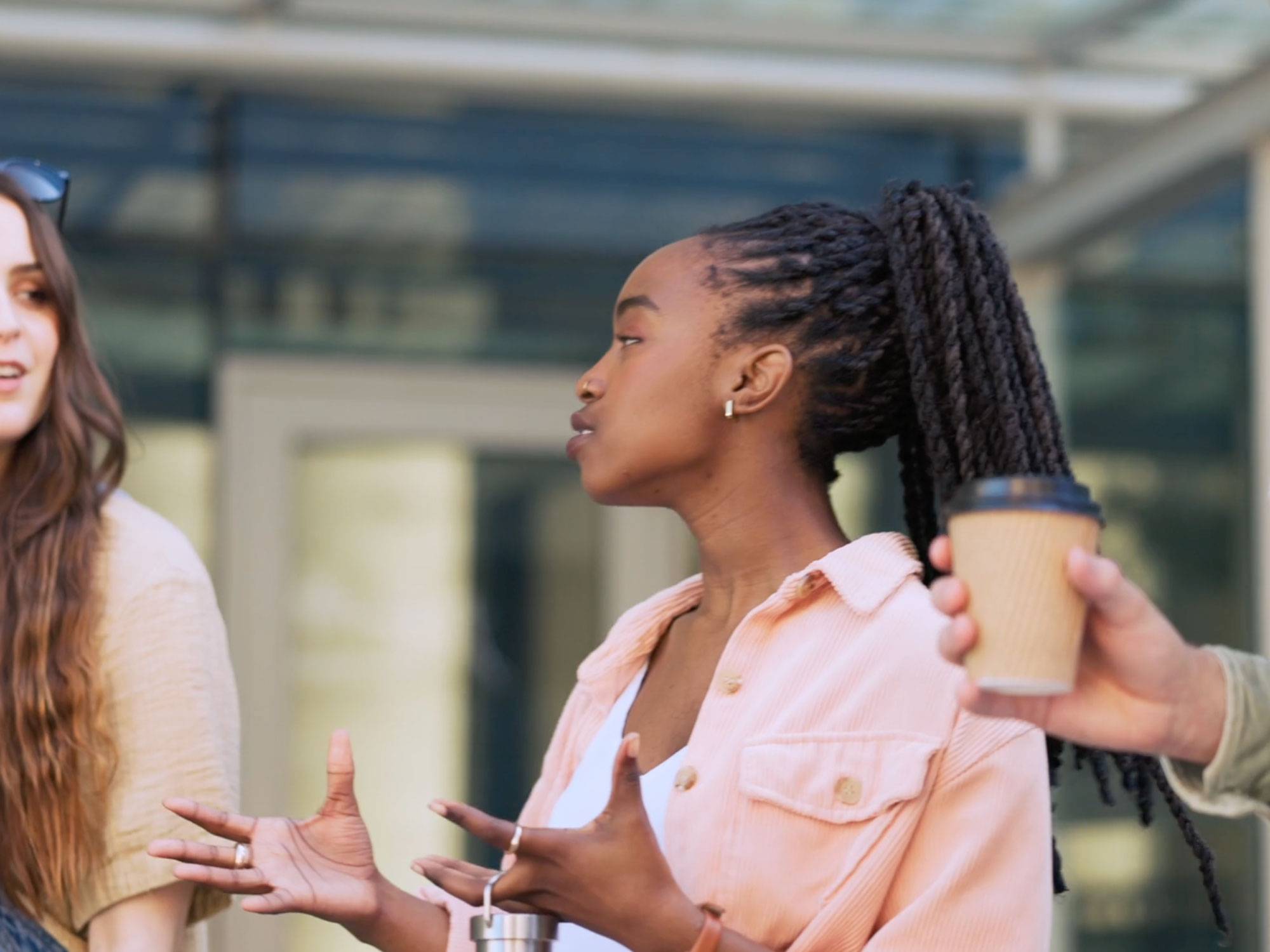 A person walks with another in the corner view, holding our their hands in discussion. 