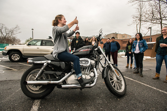MB107 Students take turns behind the wheel of a harley-davidson motorcycle for research