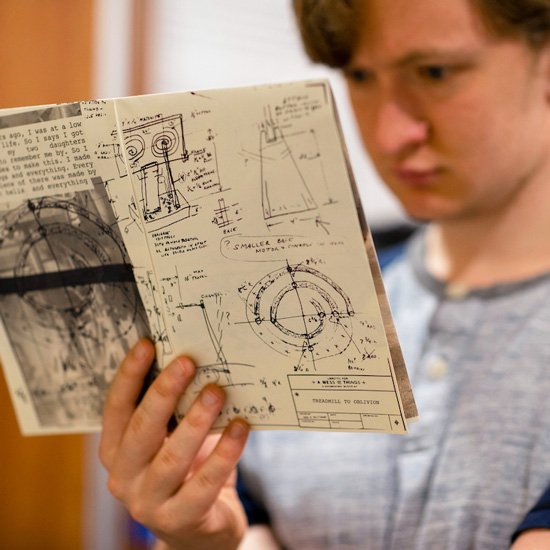 A+college+student+examines+a+book+filled+with+hand-drawn+engineering+diagrams+