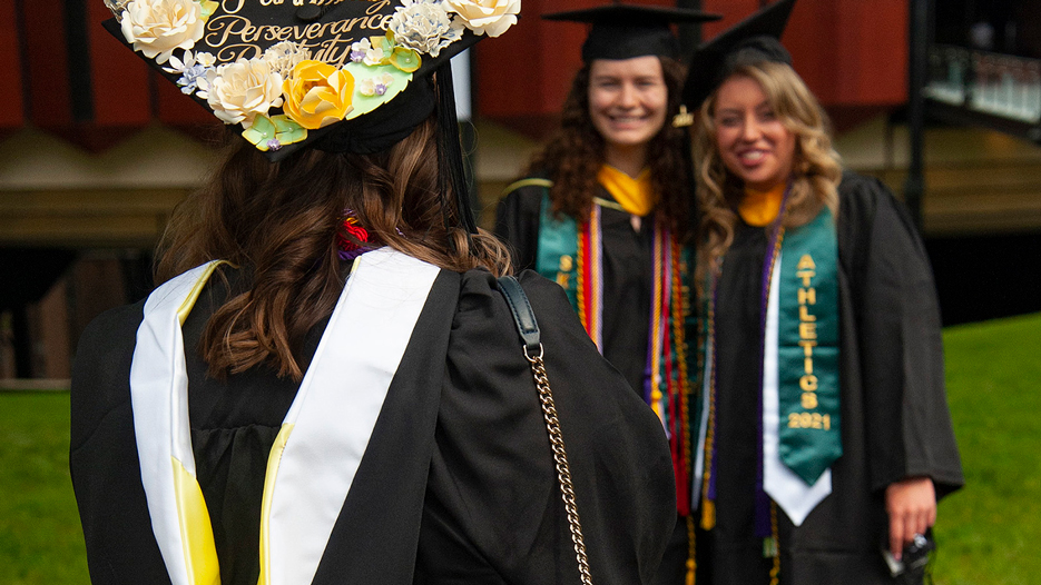Three female college graduates in undergraduate regalia 