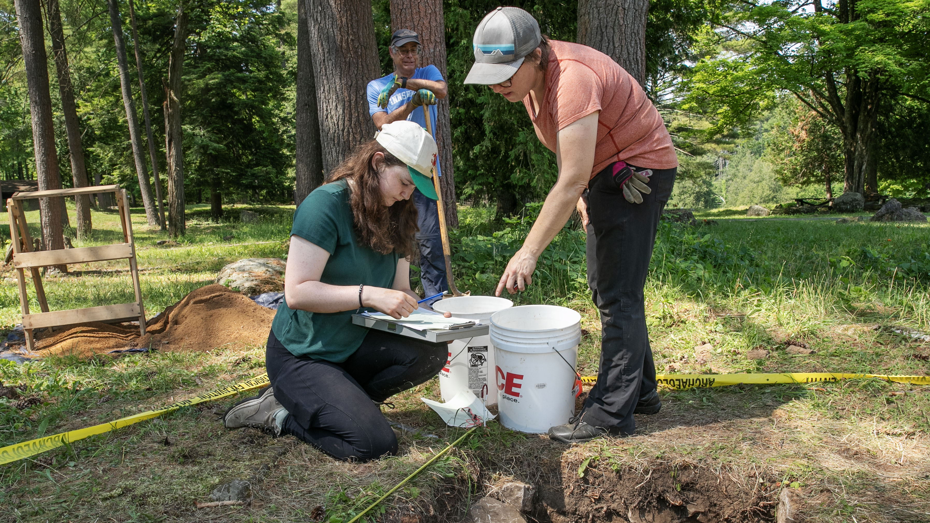 Cerys Forster ’26 and Associate Professor and Chair of Anthropology Siobhan Hart work with a volunteer to excavate a site in Lake George Battlefield Park.