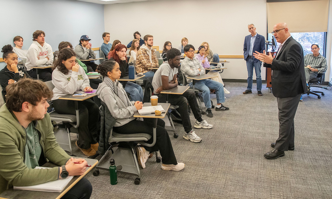 Fred Guttenberg ’88 speaks as former Republican U.S. Rep. Joe Walsh (standing) listens in a political science course taught by Associate Professor Ron Seyb (seated).
