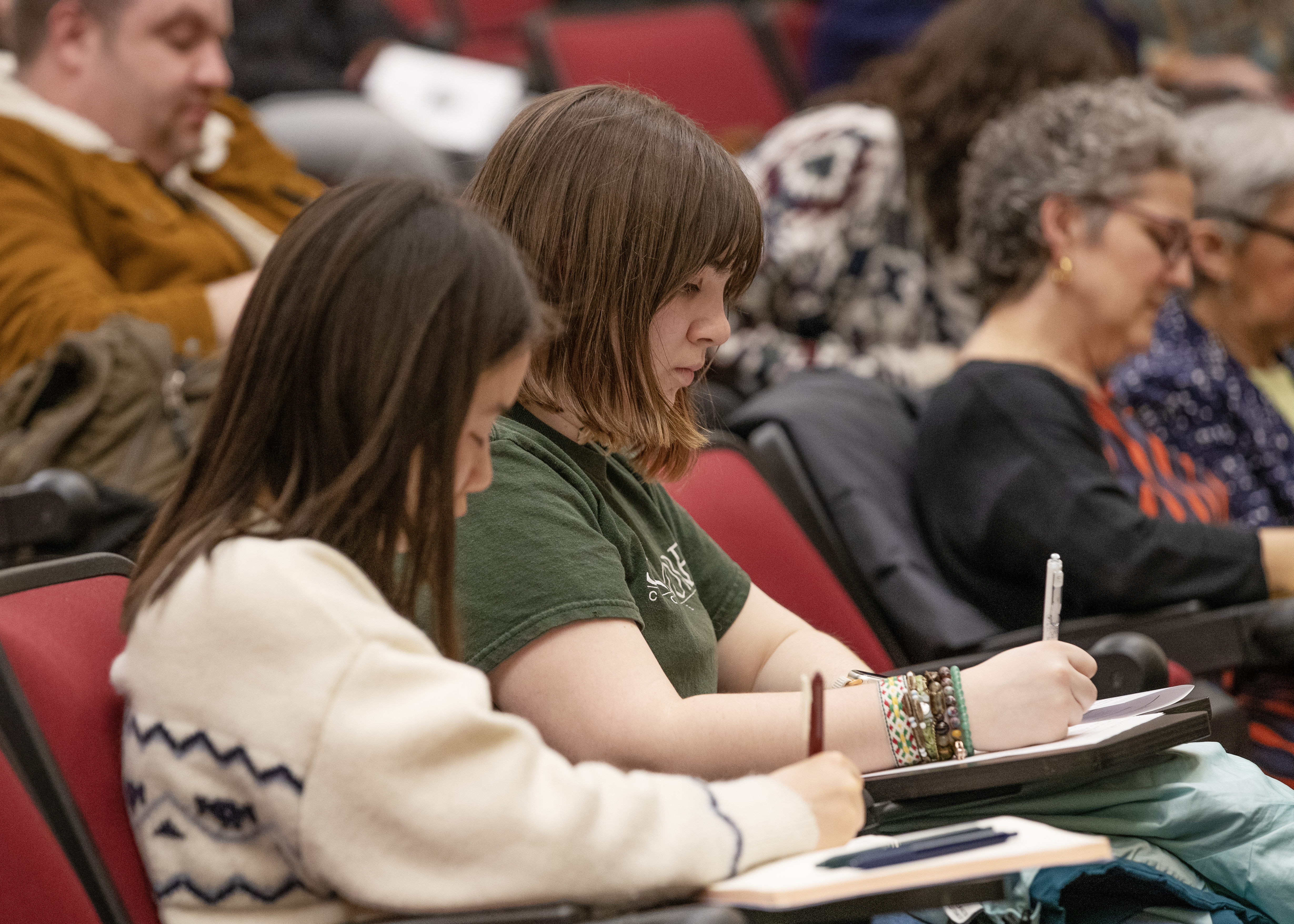 Two students take notes during Ross Douthat's talk.