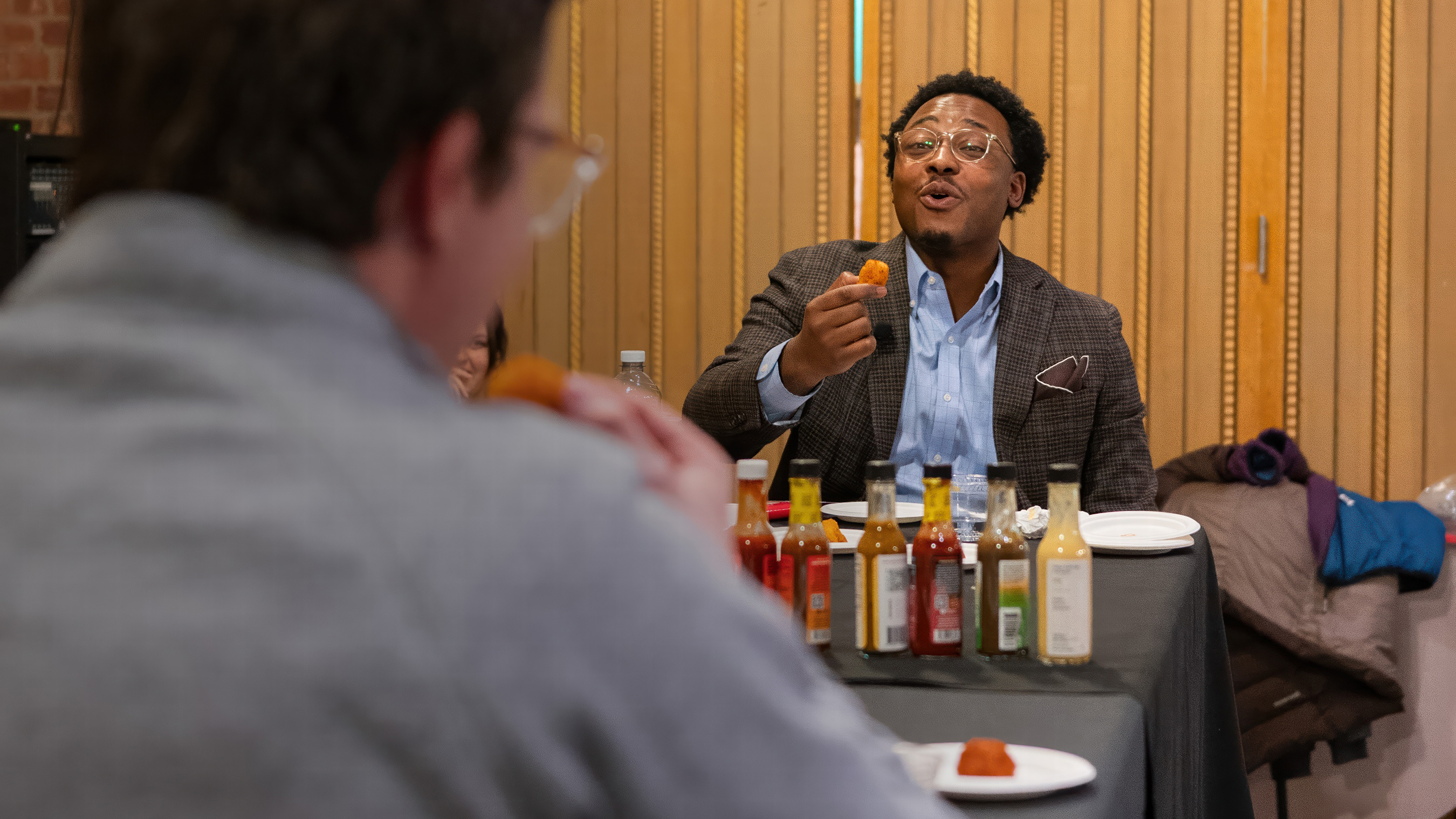 Nigel Smith ’19 holds a "wing" up to his mouth during the "Hot Ones" challenge, Austin Somers ’25 can be seen doing the same to the left