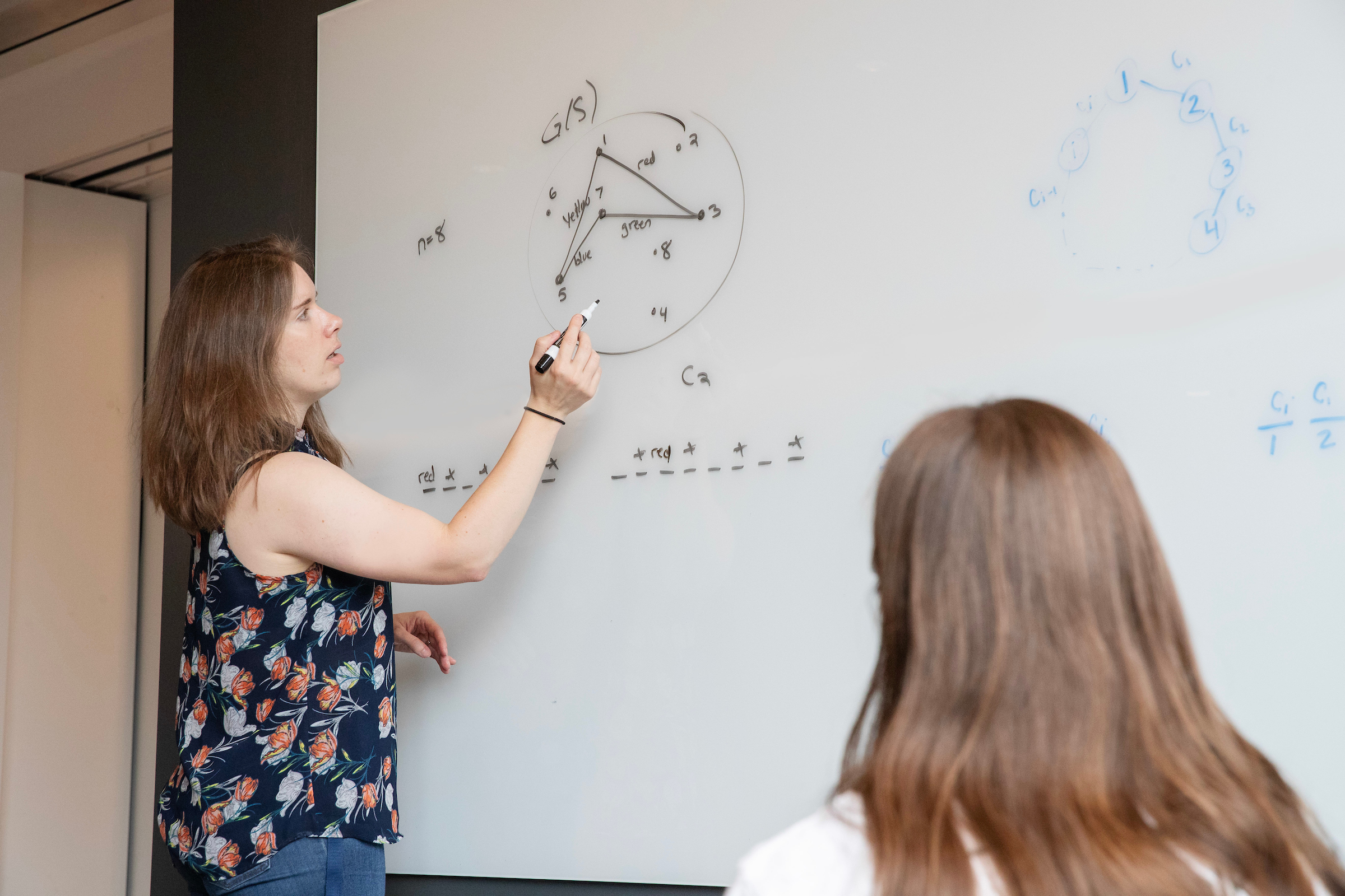 Associate Professor Kirsten Hogenson maps out Mastermind strategies on the whiteboard during a summer research session.