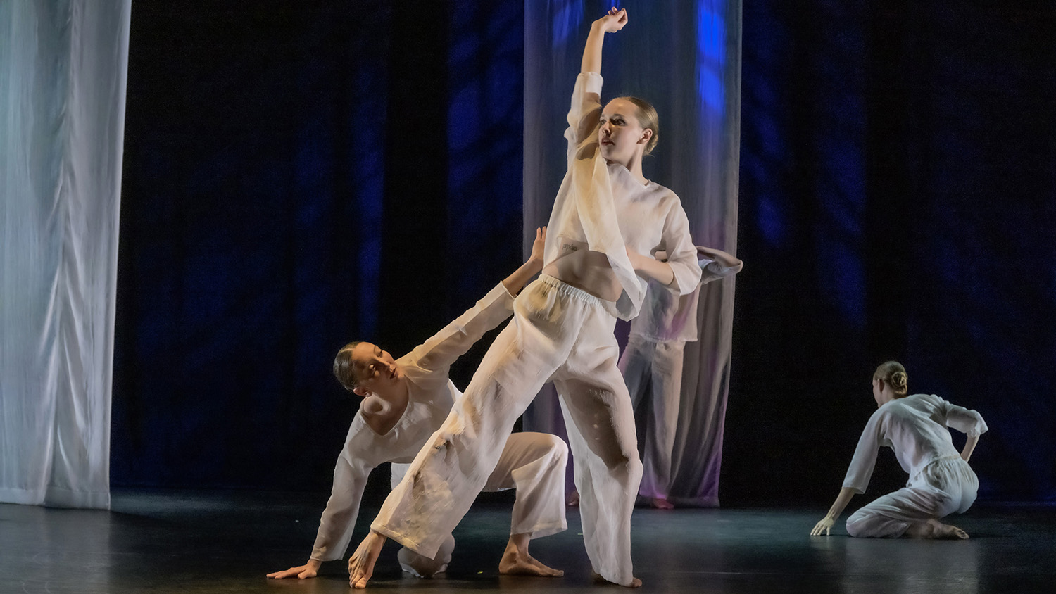 Emily Gunter dances, wearing all white — surrounded by three other similarly dressed dancers. Photo by Gary Gold.