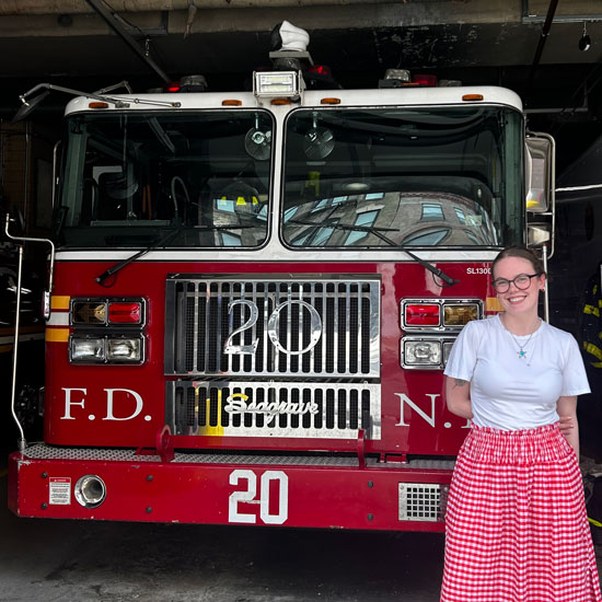 Skidmore+alumna+Lily+Ross+stands+in+front+of+a+firetruck+and+smiles+for+a+photo.+