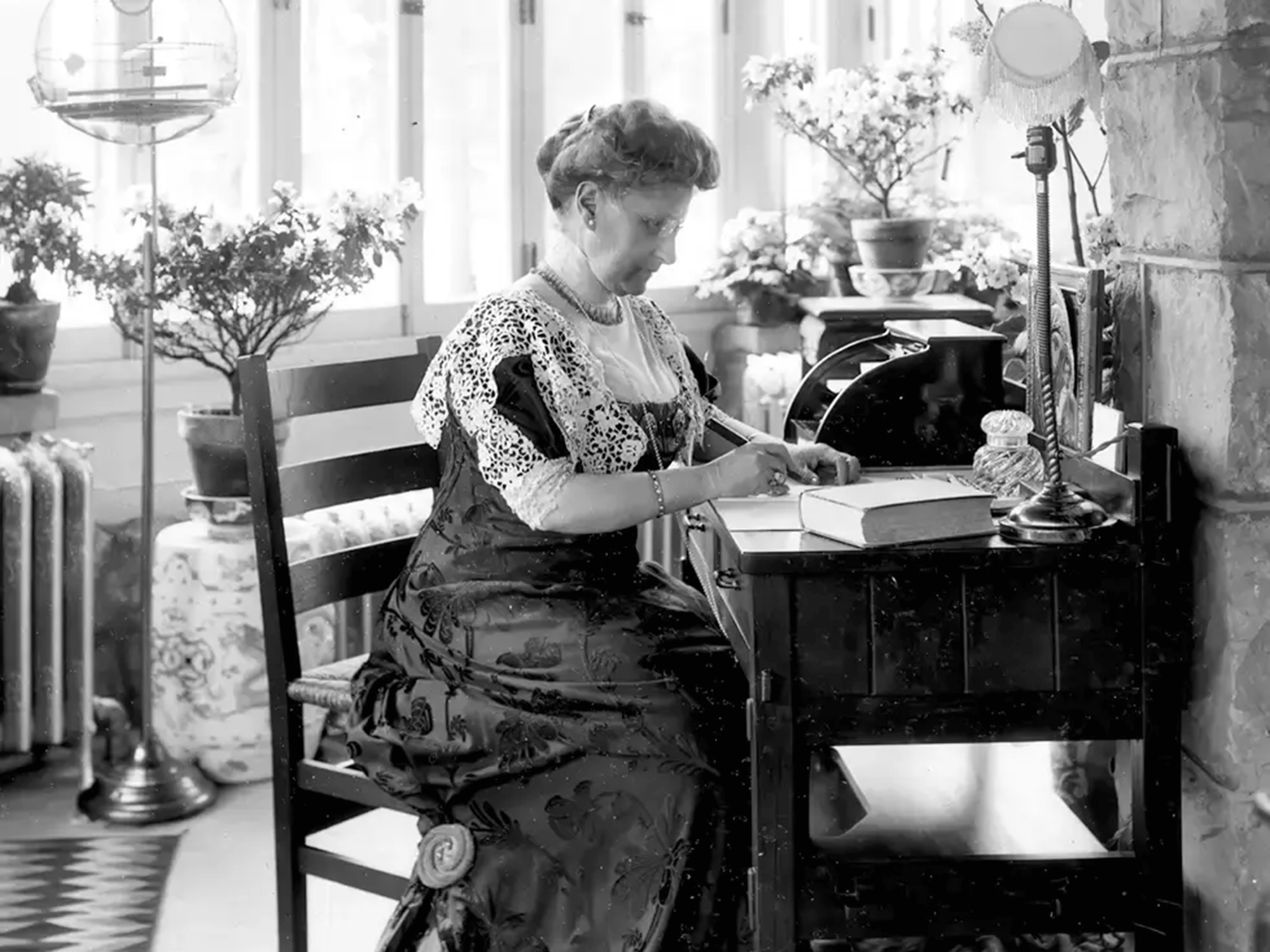 A historic black and white photo of Lucy Scribner writing at her desk. 
