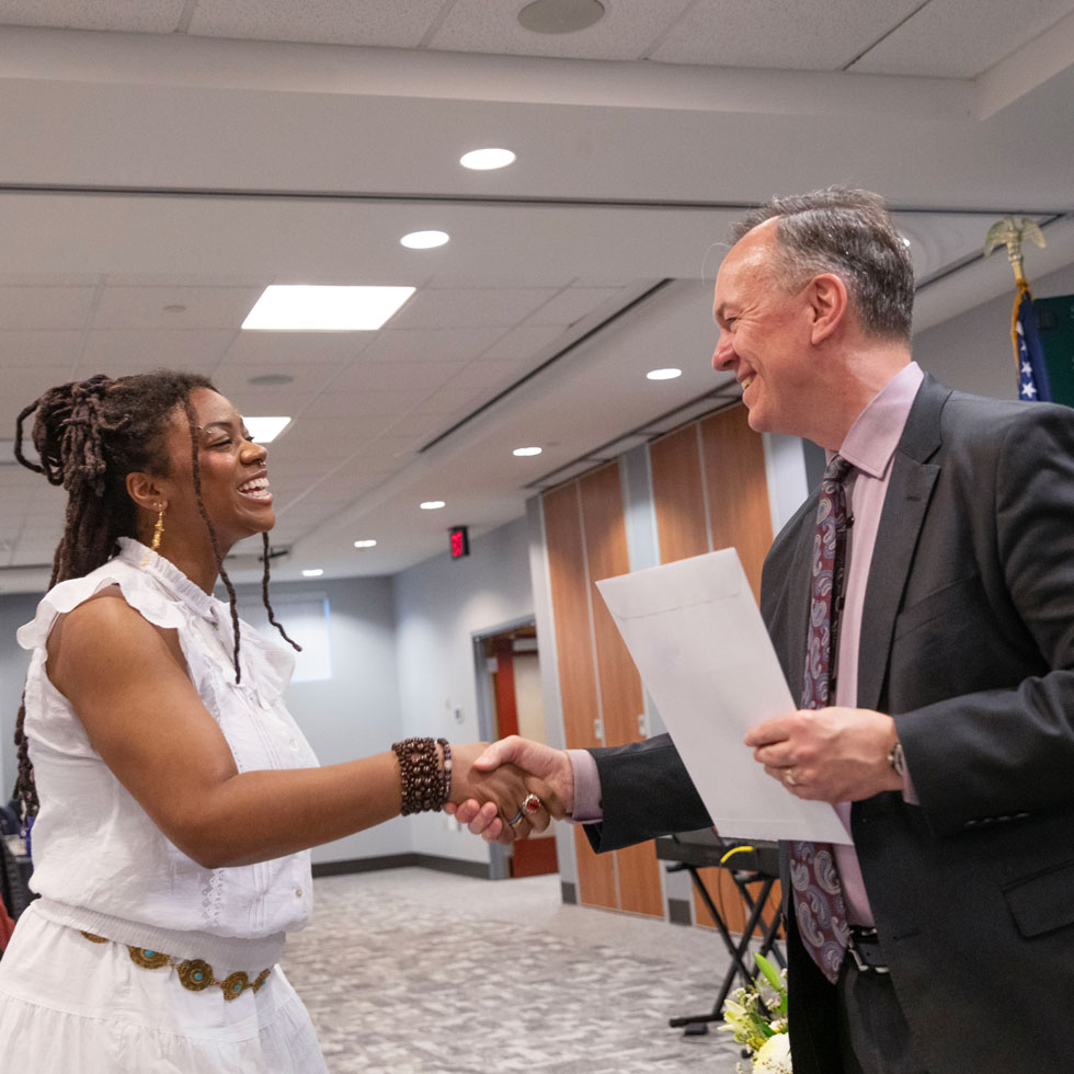 President Conner shakes hands with a student being presented with an award.