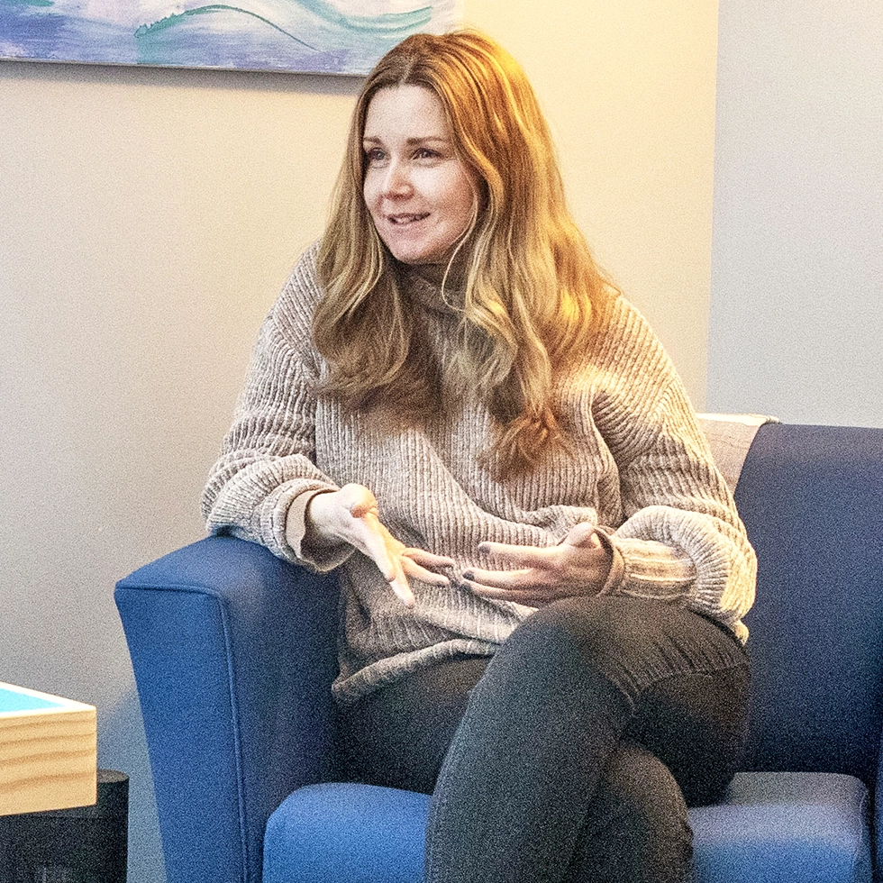 A Skidmore student sits in a blue armchair during a relaxed conversation with a mental health counselor.