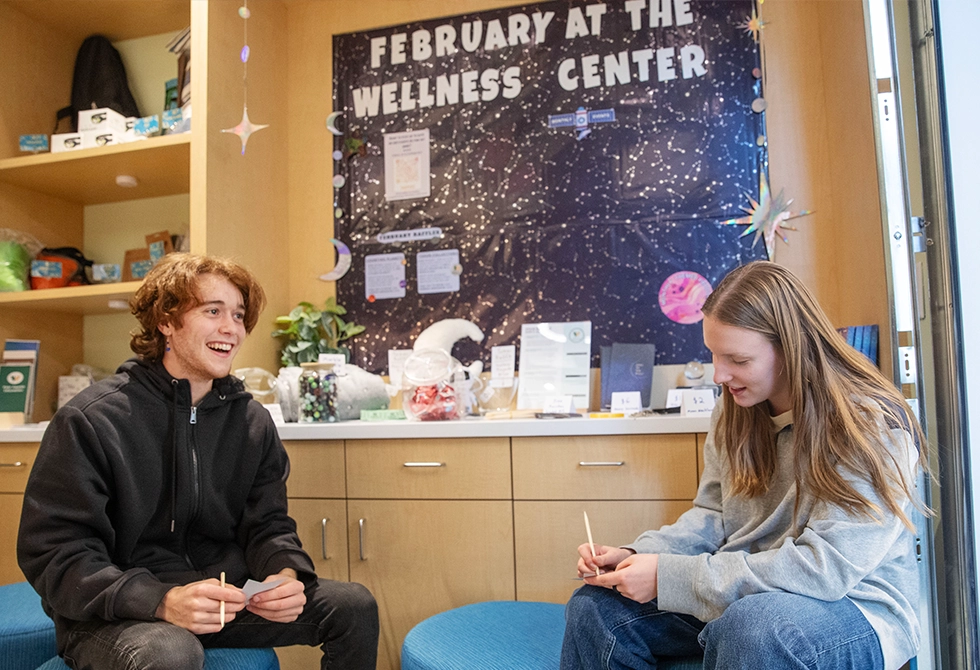 Two students sitting down smiling and talking in Skidmore's wellness center