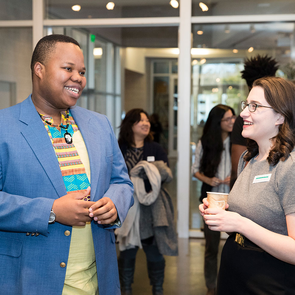 Two students smile while talking in the gallery space of the Tang Teaching Museum and Art Gallery
