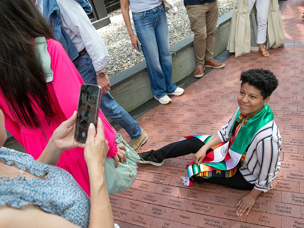 Student sits near their brick engraved with their name on Case Walkway
