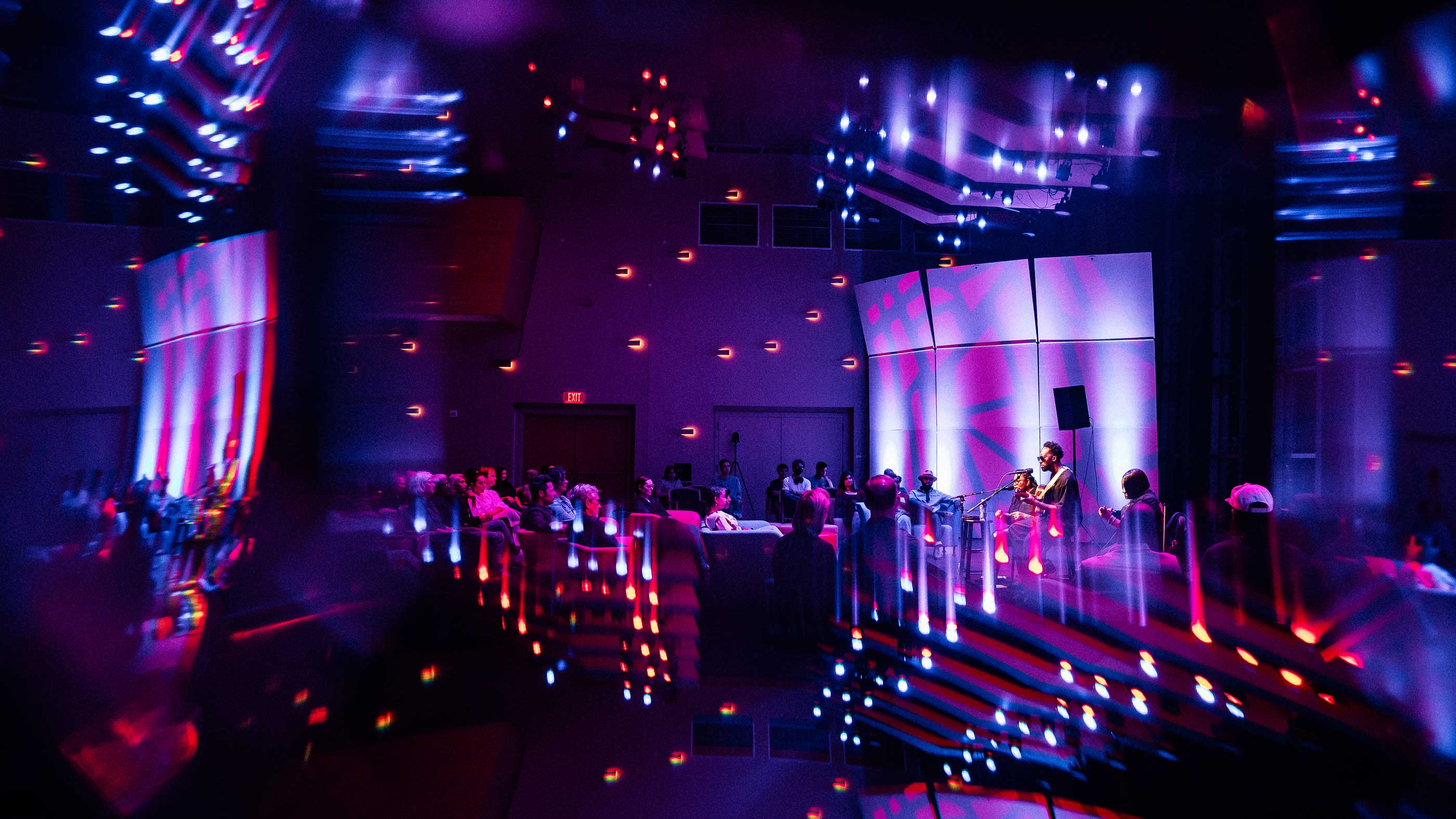 Musicians perform for an audience inside Skidmore’s Zankel Music Center, surrounded by colorful purple, blue, and red stage lighting.